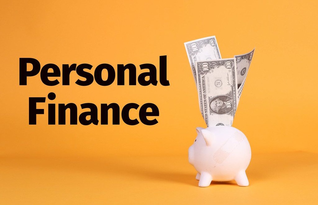 En vit spargris med dollarsedlar mot en orange bakgrund och texten 'Personal Finance'.