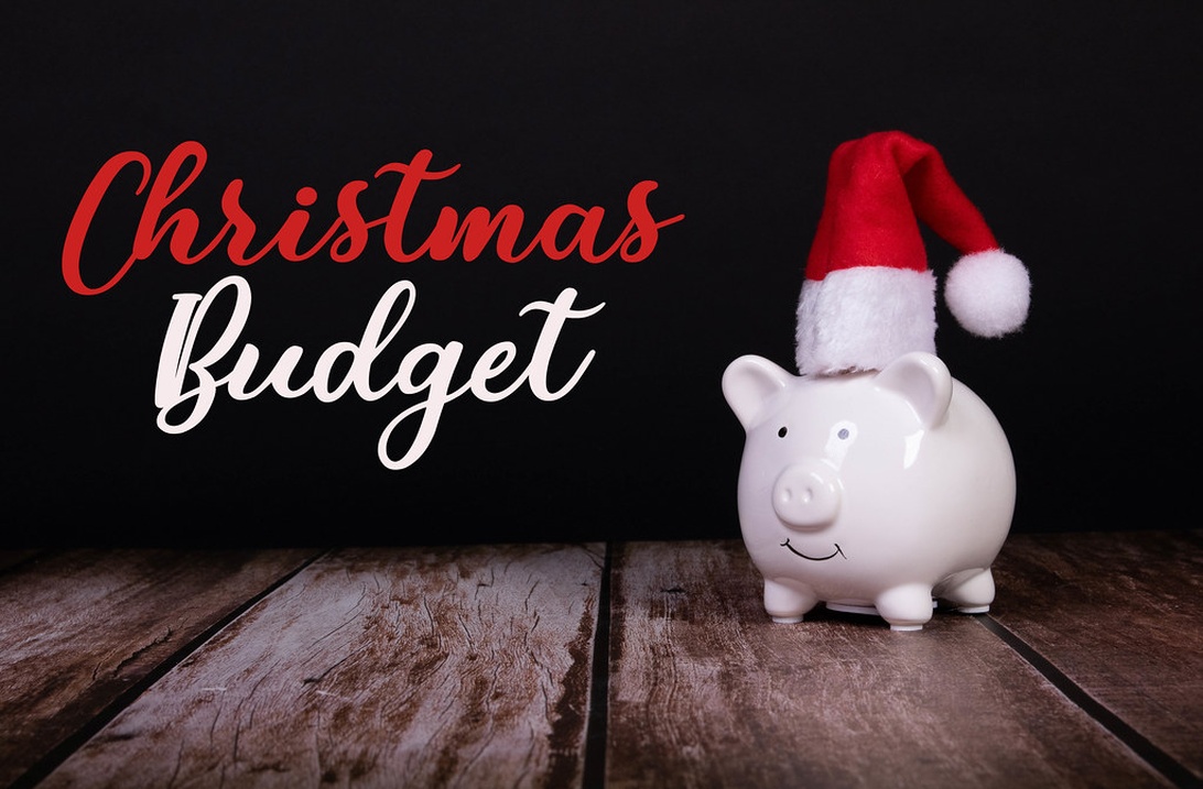 En vit spargris med tomteluva och texten 'Christmas Budget', som representerar säsongsplanering.