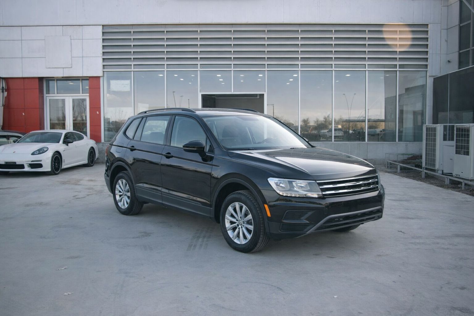 Svart SUV parkerad framför en bilhall vid ett företagsköp.